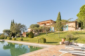 A Mediterranean-style villa with a swimming pool, outdoor seating, and lush landscaping.