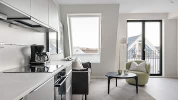 A modern kitchen with a built-in oven, a coffee machine, and a dining area with a table and chairs.