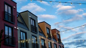A row of modern multi-story buildings with balconies and string lights against a partly cloudy sky. - VANDER - Pedersgata (Stavanger)