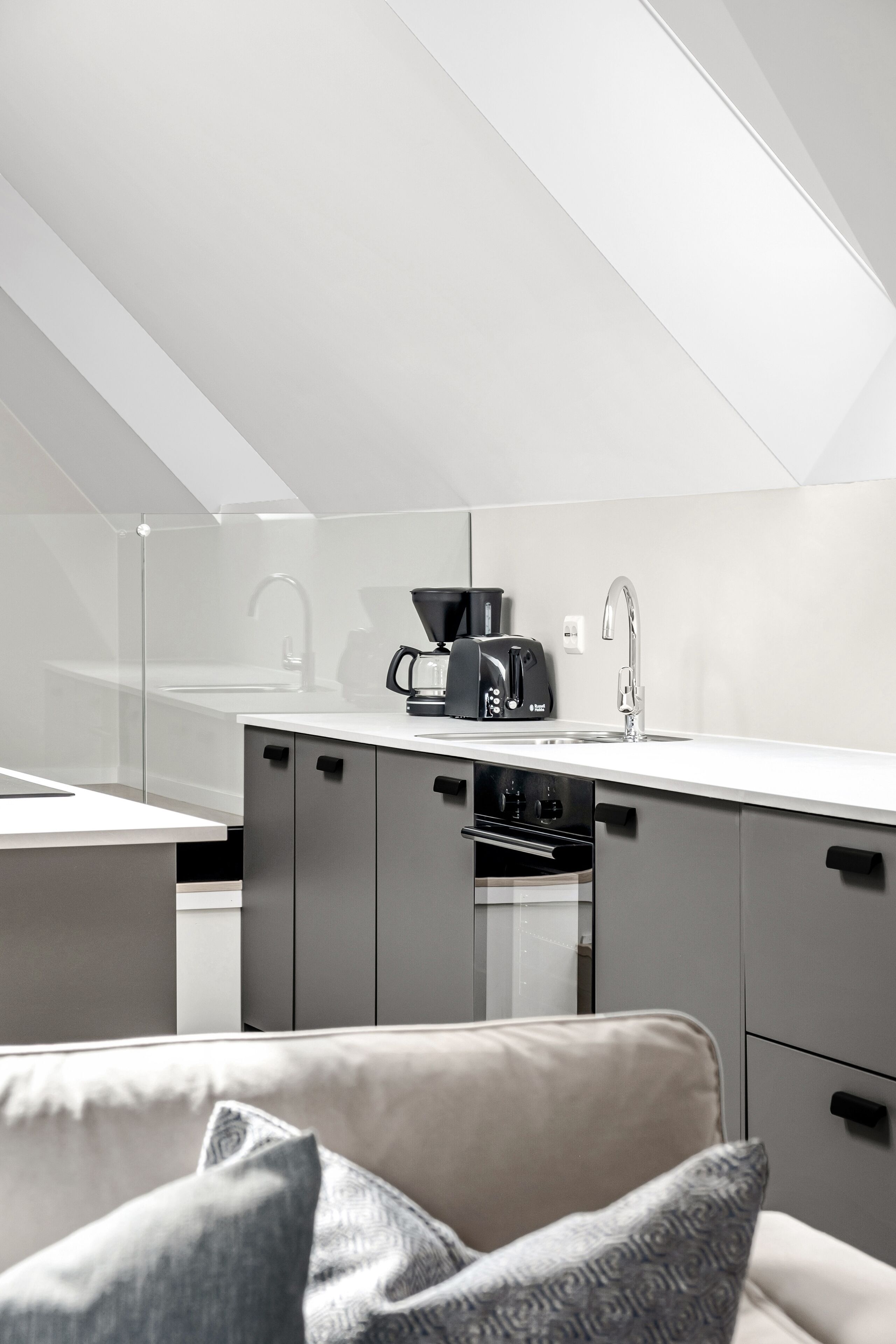 A modern kitchen with a white countertop, a coffee maker, and a toaster.