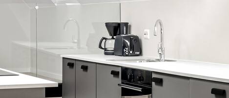 A modern kitchen with a white countertop, a coffee maker, and a toaster.