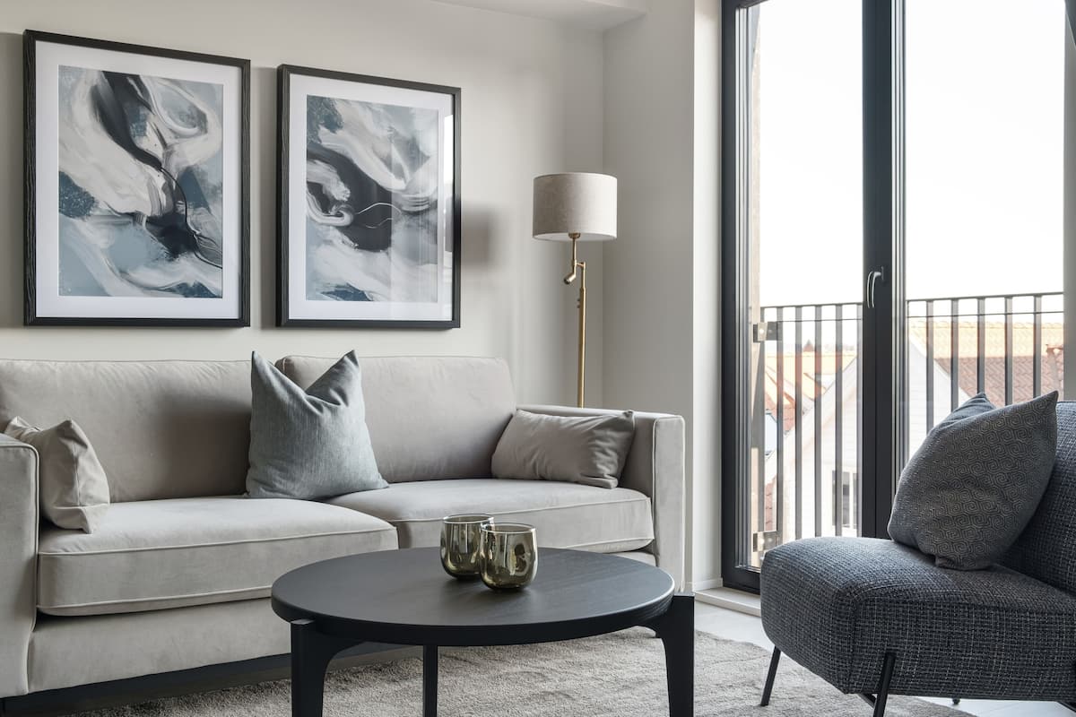 A modern living room with a sofa, a round coffee table, and two framed abstract paintings.