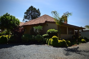 A single-story house with a red-tiled roof, surrounded by well-maintained hedges and a gravel driveway. - Gracemont Guesthouse (Eldoret)