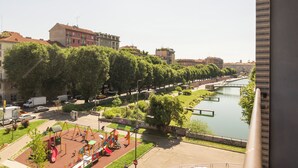 A playground with swings and slides, a river, and buildings in the background.