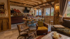 A rustic wooden interior with a dining area, wooden furniture, and a view of mountains through large windows. - Les Gets, Luxury duplex apartment with Jacuzzi (Les Gets)