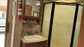 Baño con lavabo, espejo y cabina de ducha.