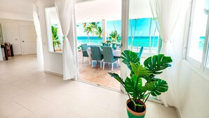 Amplia habitación con un gran ventanal corredero que da a un balcón con vistas al océano y palmeras.
