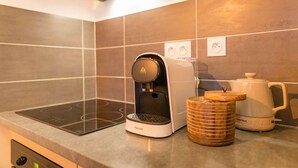 Ett modernt kök med en inbyggd induktionshäll, en kaffebryggare från Philips och en vattenkokare på bänkskivan.