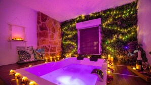 Ett rum med en vägg av sten, ett massagebord och en väggmonterad luftkonditioneringsanläggning.