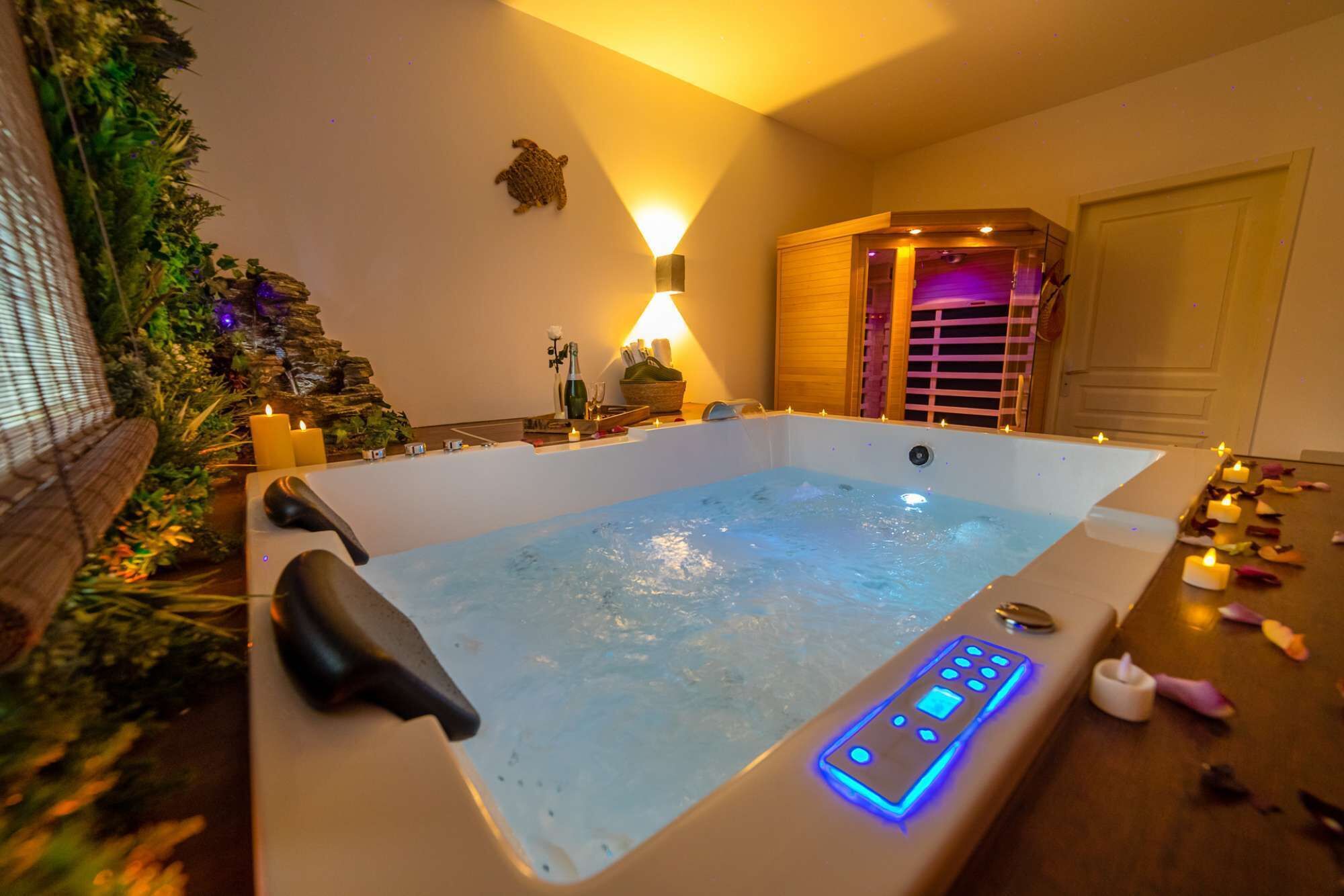 Um quarto de spa com hidromassagem, painel de controle, velas e uma pequena cascata.