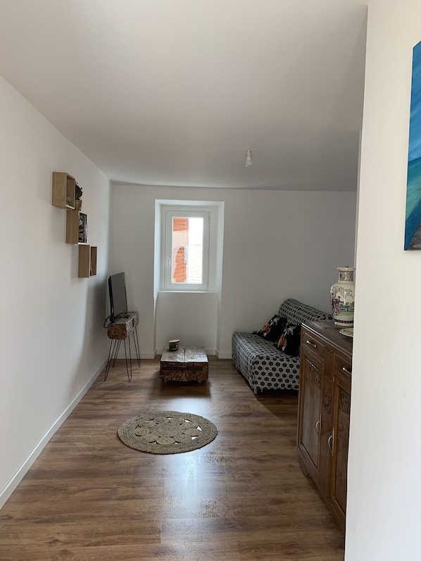 A spacious living room with a wooden floor, a sofa, a coffee table, and a cabinet.
