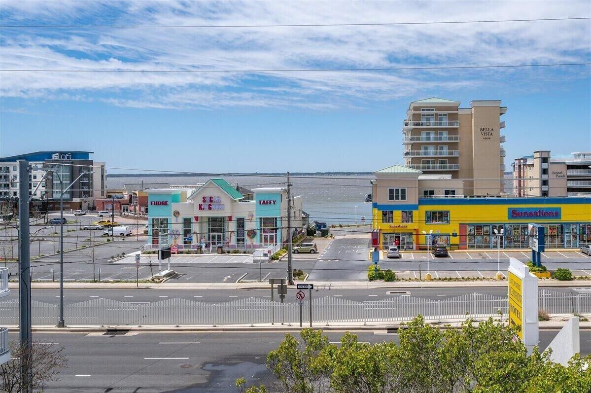 A coastal hotel with multiple floors, a parking lot, and a view of the ocean.