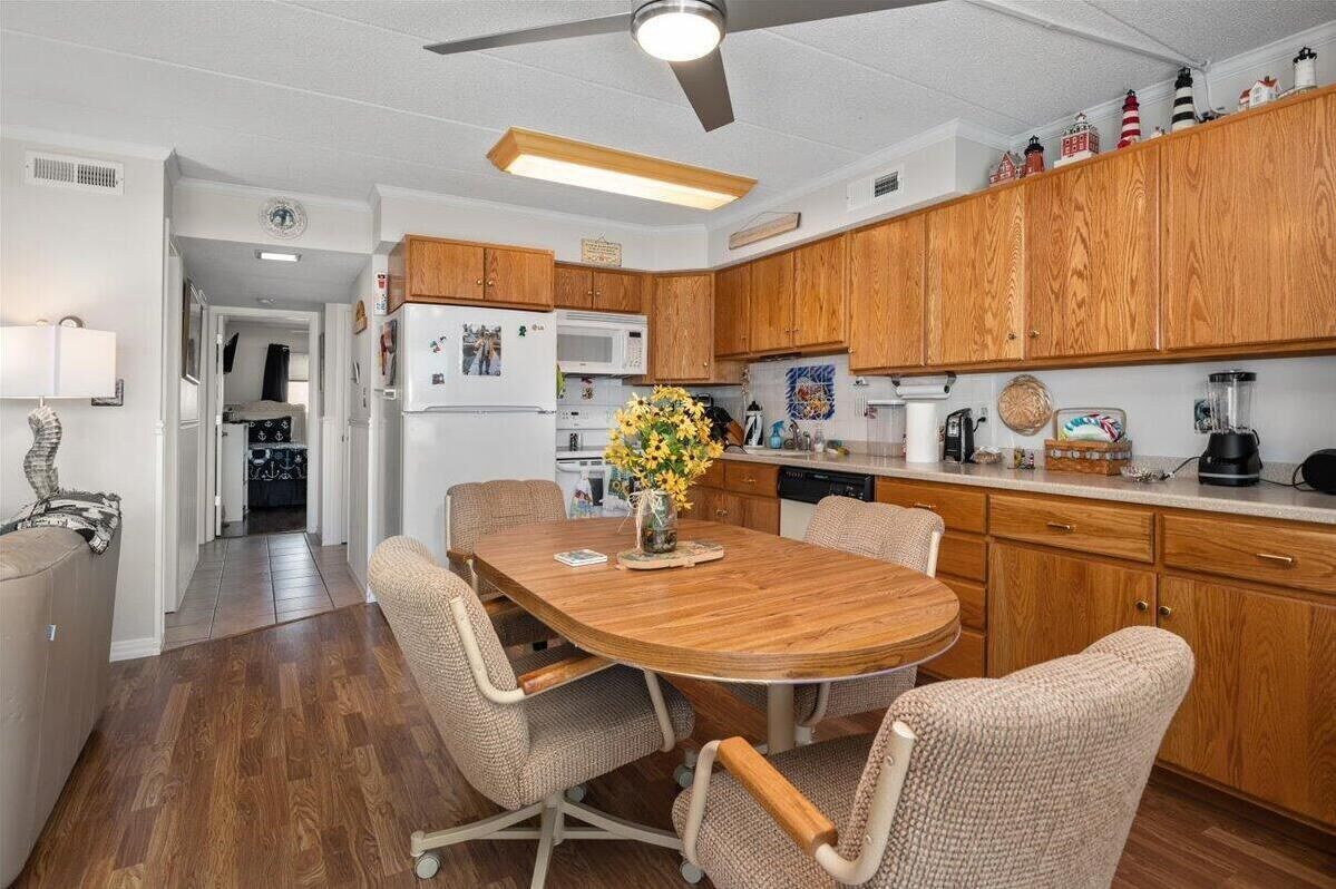 Cocina compacta con armarios de madera, un microondas y una mesa de comedor con sillas.