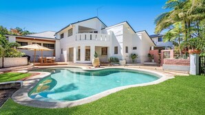 A modern two-story house with a swimming pool, surrounded by well-maintained lawn and tropical plants. - Le Dog Beach Club - chic home with pool (Byron Bay)
