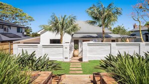 A modern house with a white exterior, a grey roof, and a paved driveway leading to a front door. - Le Dog Beach Club - chic home with pool (Byron Bay)