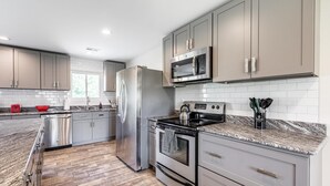 A modern kitchen with stainless steel appliances, grey cabinets, and a granite countertop. - Cozy, Clean and Bright 4BR / 2BA Home! Welcome! (Sterling Heights)