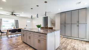 A modern kitchen with a central island, pendant lights, and built-in cabinets. - Cozy, Clean and Bright 4BR / 2BA Home! Welcome! (Sterling Heights)