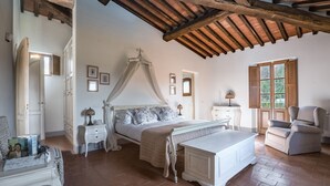 Una camera da letto con un letto a baldacchino, un comodino, una sedia e una finestra vista verde.