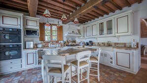 Un'ampia cucina con una grande isola, travi in legno e mobili bianchi.