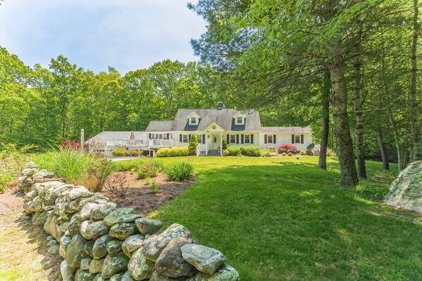 A large, two-story house with a well-maintained lawn and stone wall.