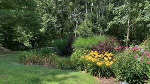 Un jardin agrémenté de diverses plantes et fleurs, un petit étang et une statue.