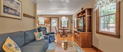 A spacious living room with a blue sofa, a wooden coffee table, and a ceiling fan.
