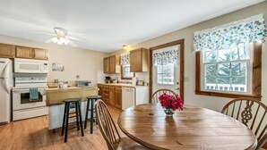 Une cuisine avec des meubles de rangement en bois, un four à micro-ondes, un four traditionnel, un évier et une table à manger avec des chaises.