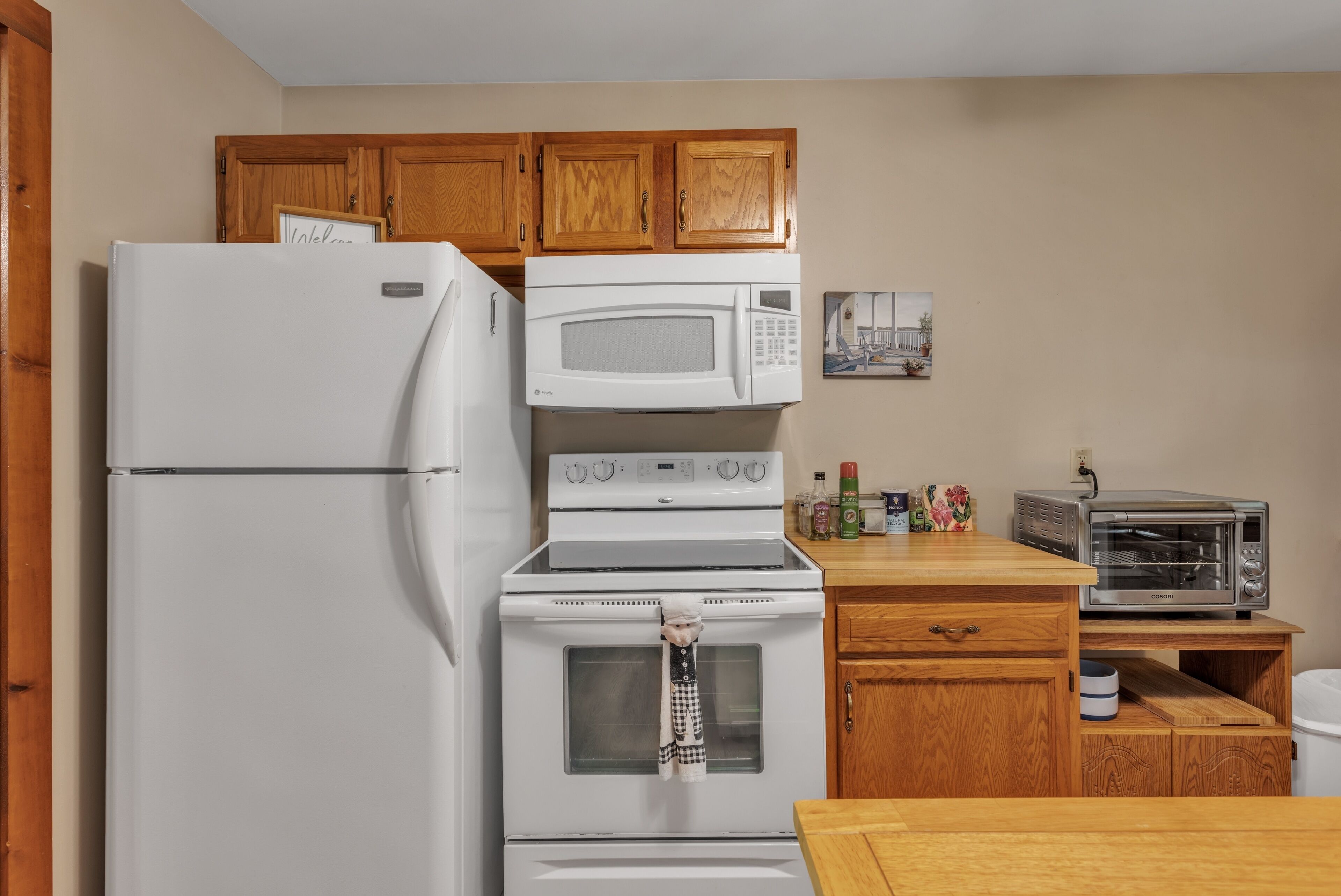 A kitchen with a refrigerator, microwave, oven, and toaster.