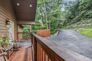A wooden deck with rocking chairs and a mailbox, overlooking a winding road and forested hillside. - Roundtop Mountain Ridge 2 Bedroom Cabin by RedAwning (Sevierville)