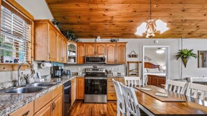 A kitchen with wooden cabinets, a stainless steel oven, and a granite countertop. - Roundtop Mountain Ridge 2 Bedroom Cabin by RedAwning (Sevierville)