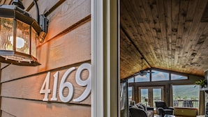 A wooden exterior with the number 4169, a cozy interior with seating and a view of the outdoors. - Roundtop Mountain Ridge 2 Bedroom Cabin by RedAwning (Sevierville)