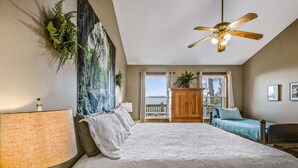 A bedroom with a large bed, a ceiling fan, a window with a view, and a wooden cabinet. - Roundtop Mountain Ridge 2 Bedroom Cabin by RedAwning (Sevierville)