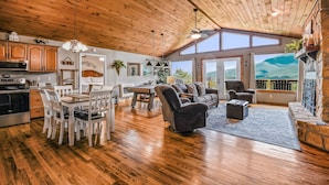 A spacious living area with wooden flooring, a dining table, and a fireplace. - Roundtop Mountain Ridge 2 Bedroom Cabin by RedAwning (Sevierville)