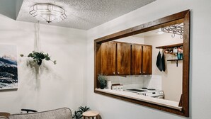 Une cuisine moderne avec des meubles en bois, un luminaire suspendu et une vue sur le salon.