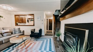 Un salon moderne avec un canapé, une table basse et une cheminée. Un escalier mène à un autre niveau.