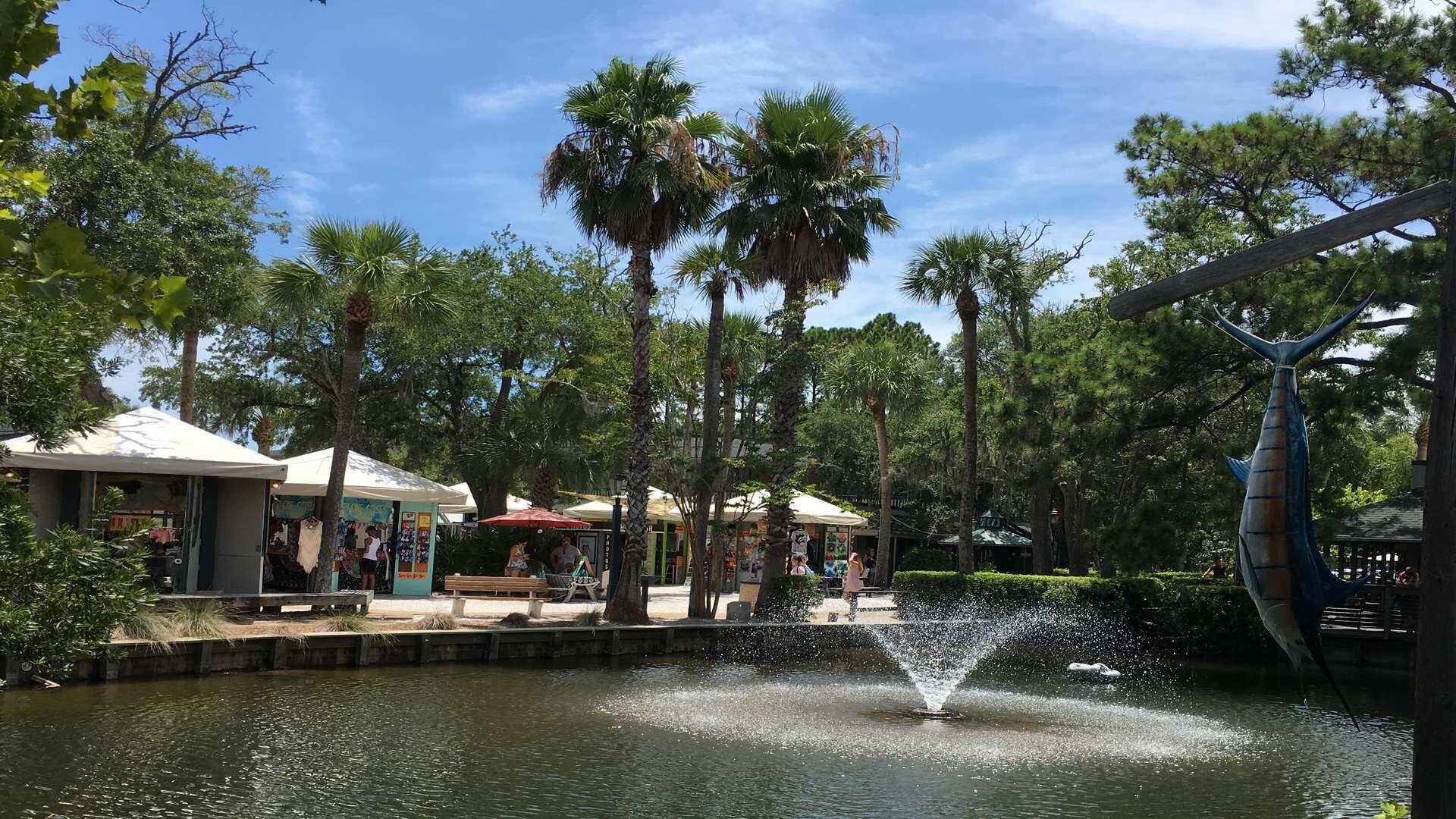 Un parc doté d’une fontaine, de palmiers et d’espaces aménagés pour se détendre en plein air.