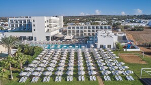 Ein Hotel mit großzügigem Poolbereich, zahlreichen Liegestühlen und Sonnenschirmen.