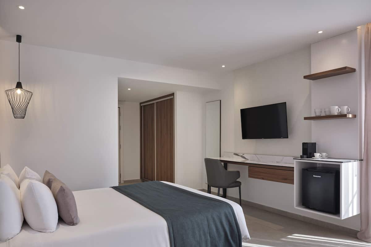 Una habitación de hotel moderna con cama, escritorio y kitchenette.