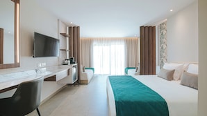 Ein Hotelzimmer mit Bett, Schreibtisch, Stuhl, Fernseher und einem Fenster mit Vorhängen.