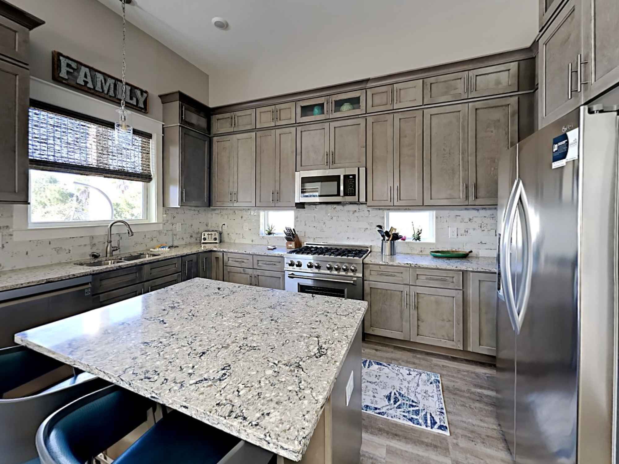 A kitchen with granite countertops, stainless steel appliances, and a central island.