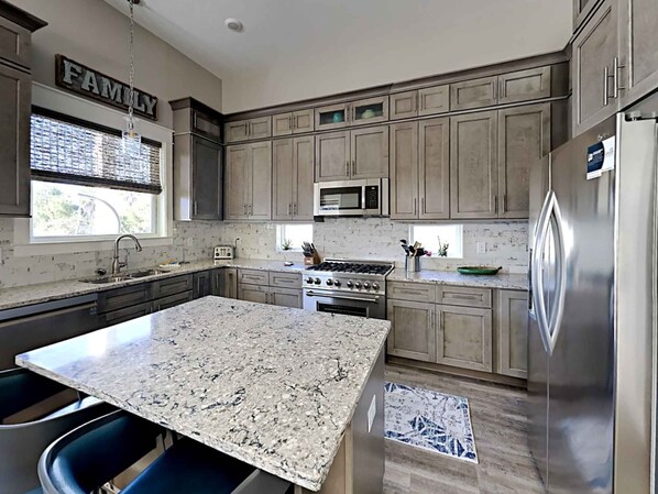 A modern kitchen with granite countertops, stainless steel appliances, and a central island.