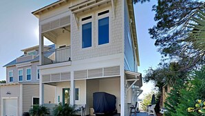 A two-story house with a covered patio, a garage, and a small garden area. - View from the Top  -  4 Bikes, Golf Cart, Views! (Santa Rosa Beach)