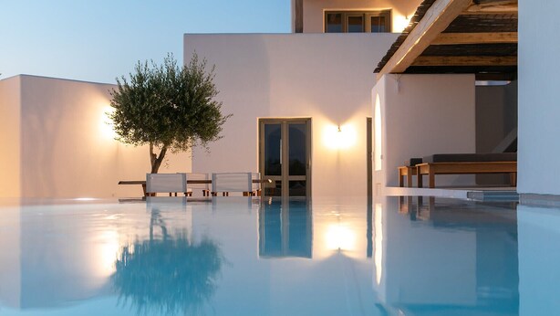Et moderne poolområde med klart, blåt vand, en træterrasse og et minimalistisk design.