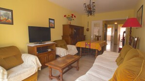 Un salon comprenant un canapé, un téléviseur, un meuble en bois et une table à manger.