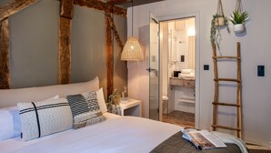 A bedroom with a large bed, a bedside table, a hanging light fixture, and a wooden ladder against the wall. - Hotel Fuchs (Saarbrücken)