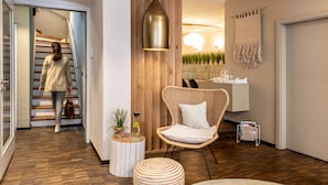 A modern interior with a wooden staircase, a wicker chair, a round side table, and a pendant light. - Hotel Fuchs (Saarbrücken)