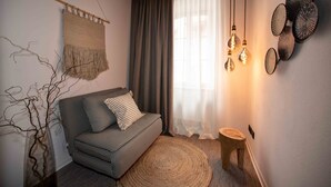 A cozy living room with a sofa, a woven rug, and a wall-mounted light fixture. - Hotel Fuchs (Saarbrücken)