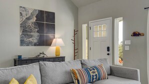 A living room with a grey sofa, a lamp, a coat rack, and a door leading to an outdoor area. - Experience hill country life & relax! Family & Pet Friendly near Canyon Lake. (Canyon Lake)
