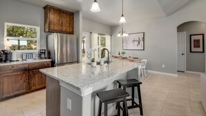 A spacious kitchen with granite countertops, wooden cabinets, and stainless steel appliances. - Experience hill country life & relax! Family & Pet Friendly near Canyon Lake. (Canyon Lake)