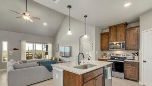 A modern kitchen with a central island, wooden cabinets, and a built-in microwave. - Experience hill country life & relax! Family & Pet Friendly near Canyon Lake. (Canyon Lake)